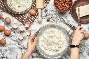 Close-up shot. Top view of a baker cook place, hands are working with a raw dough on the marble table background. photo