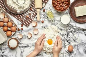 Close-up shot. Top view of a baker cook place, hands are working with a raw dough on the marble table background. photo