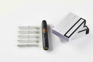 New generation black electronic cigarette, two packs with purple sides and five heatsticks isolated on white. Hi-tech heating tobacco system. Close up photo