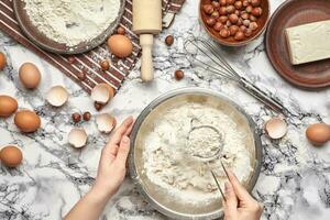 Close-up shot. Top view of a baker cook place, hands are working with a raw dough on the marble table background. photo