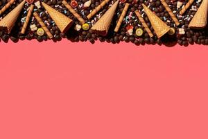 Chocolate dragee and waffle cones placed in fascinating order on coral background, view from above photo