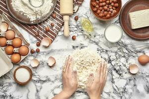 Close-up shot. Top view of a baker cook place, hands are working with a raw dough on the marble table background. photo