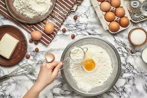 Close-up shot. Top view of a baker cook place, hands are working with a raw dough on the marble table background. photo