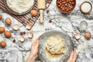 Close-up shot. Top view of a baker cook place, hands are working with a raw dough on the marble table background. photo