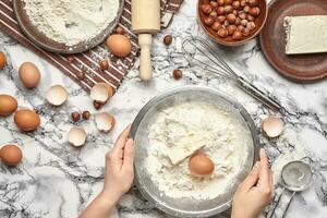 Close-up shot. Top view of a baker cook place, hands are working with a raw dough on the marble table background. photo