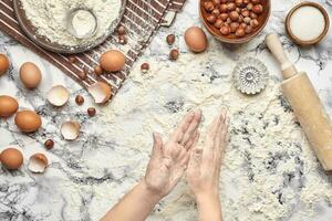 Close-up shot. Top view of a baker cook place, hands are working with a raw dough on the marble table background. photo