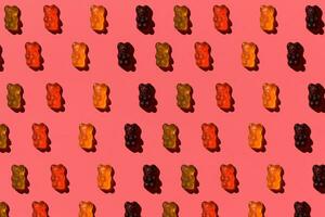 Pattern made of colorful jelly bears on coral background. Flat lay. Minimal concept photo