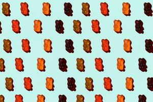 Pattern made of colorful jelly bears on aquamarine background. Flat lay. Minimal concept photo