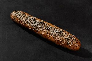 Fresh, tasty baked bread with black and white sesame seeds against dark background with copy space. Rural cuisine or bakery. Close-up photo