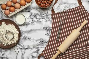 Close-up shot. Top view of a baking ingredients and kitchenware on the marble table background. photo