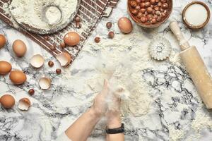 Close-up shot. Top view of a baker cook place, hands are working with a raw dough on the marble table background. photo