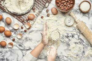 Close-up shot. Top view of a baker cook place, hands are working with a raw dough on the marble table background. photo