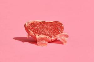 Close up high quality image of peeled slice of juicy grapefruit on a pink background photo