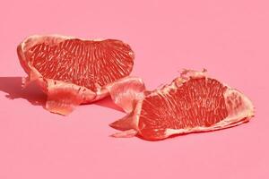 Close up high quality image of peeled slices of juicy grapefruit on a pink background photo