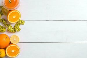 Fresh fruits with tape measure over white wooden background. Top view photo