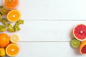 Fresh fruits with tape measure over white wooden background. Top view photo