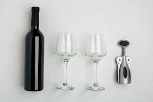 Red wine bottle, glasses and corkscrew over white background. Top view with copy space photo