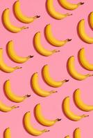 Pattern composition of a pair of bananas lying next to a pink background , top view photo