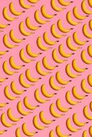 Pattern composition of yellow sweet bananas lying next to a pink background , top view photo