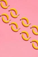 modelo composición de un par de bananas acostado siguiente a un rosado antecedentes , parte superior ver foto