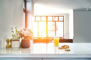 Appetizing sweet orange juice and one drinking glasses standing on a white table in the kitchen for a breakfast. photo