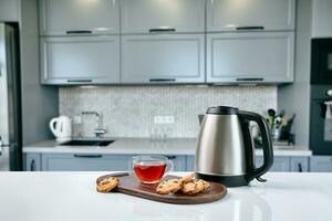 Breakfast scene at sunny morning. Transparent black tea mug with biscuit on kitchen table photo