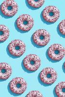 Food design with tasty pink glazed donut on blue pastel background top view pattern photo