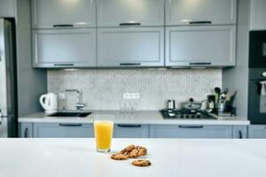 Cookies with glass of orange juice on the kitchen table, blurred background. photo