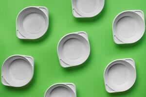 White plastic disposable tableware on green background with copy space. The concept of picnic utensil. Top view. Selective focus. Close-up. photo