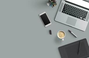 Office desk table with laptop computer, smartphone with black screen over a notebook and cup of coffee. Top view. photo