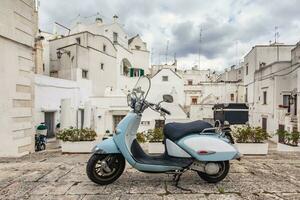 View of the old town of Martina Franca. Classic blue moped on the background of an anient buildings. photo