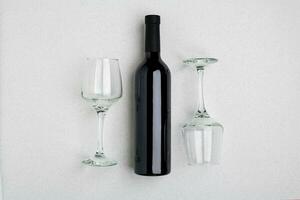 Overhead angled view of a large bottle of red wine, drinking glasses on white background photo