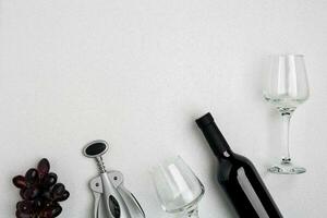 Red wine bottle, glasses and corkscrew over white background. Top view with copy space photo