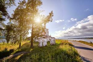 Old orthodox church at village. Summer view with floral meadow. Sun flare photo