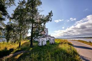 Old orthodox church at village. Summer view with floral meadow. Sun flare photo