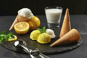 Tasty creamy and citrus lemon ice cream decorated with mint served on a stone slate over a black background. photo