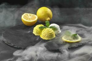 Tasty creamy and citrus lemon ice cream decorated with mint served on a stone slate over a black background. photo