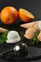 Close-up shot of a creamy and orange ice cream served on a dark slate, black background. photo