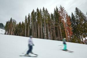 Panorama of ski resort, slope, people on the ski lift, skiers on the piste among green pine trees and snow lances. photo