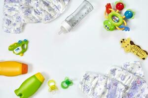 conjunto de accesorios para bebé. chupete, botella, pañal, crema en blanco antecedentes. foto