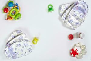 Babies goods diaper, soother or nipple on white background with copy space. Top view or flat lay. photo