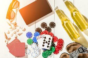 Card deck surrounded by poker chips and scattered seashells on white wooden background with copy space photo