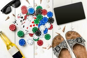 Card deck surrounded by poker chips and scattered seashells on white wooden background with copy space photo