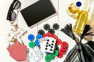 Card deck surrounded by poker chips and scattered seashells on white wooden background with copy space photo