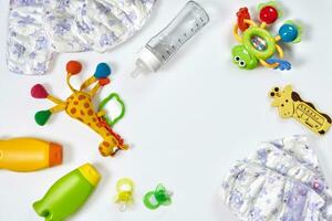 conjunto de accesorios para bebé. chupete, botella, pañal, crema en blanco antecedentes. foto