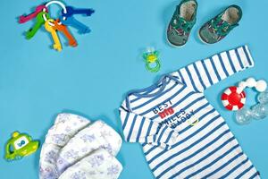 Baby clothing, toiletries, toys and health care accessories on blue background. photo