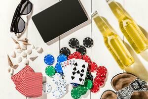 Card deck surrounded by poker chips and scattered seashells on white wooden background with copy space photo