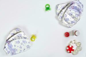 Babies goods diaper, soother or nipple on white background with copy space. Top view or flat lay. photo