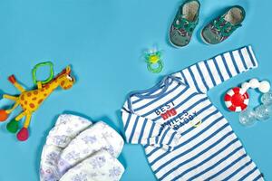Baby clothing, toiletries, toys and health care accessories on blue background. photo