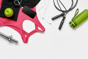 Sport, fitness, healthy lifestyle, cardio training and objects concept - close up of female sports clothing, skipping rope and bottle set photo